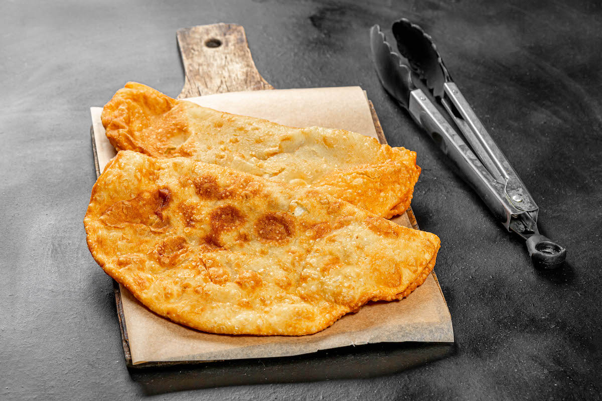 Two deep-fried turnovers on a wooden cutting board