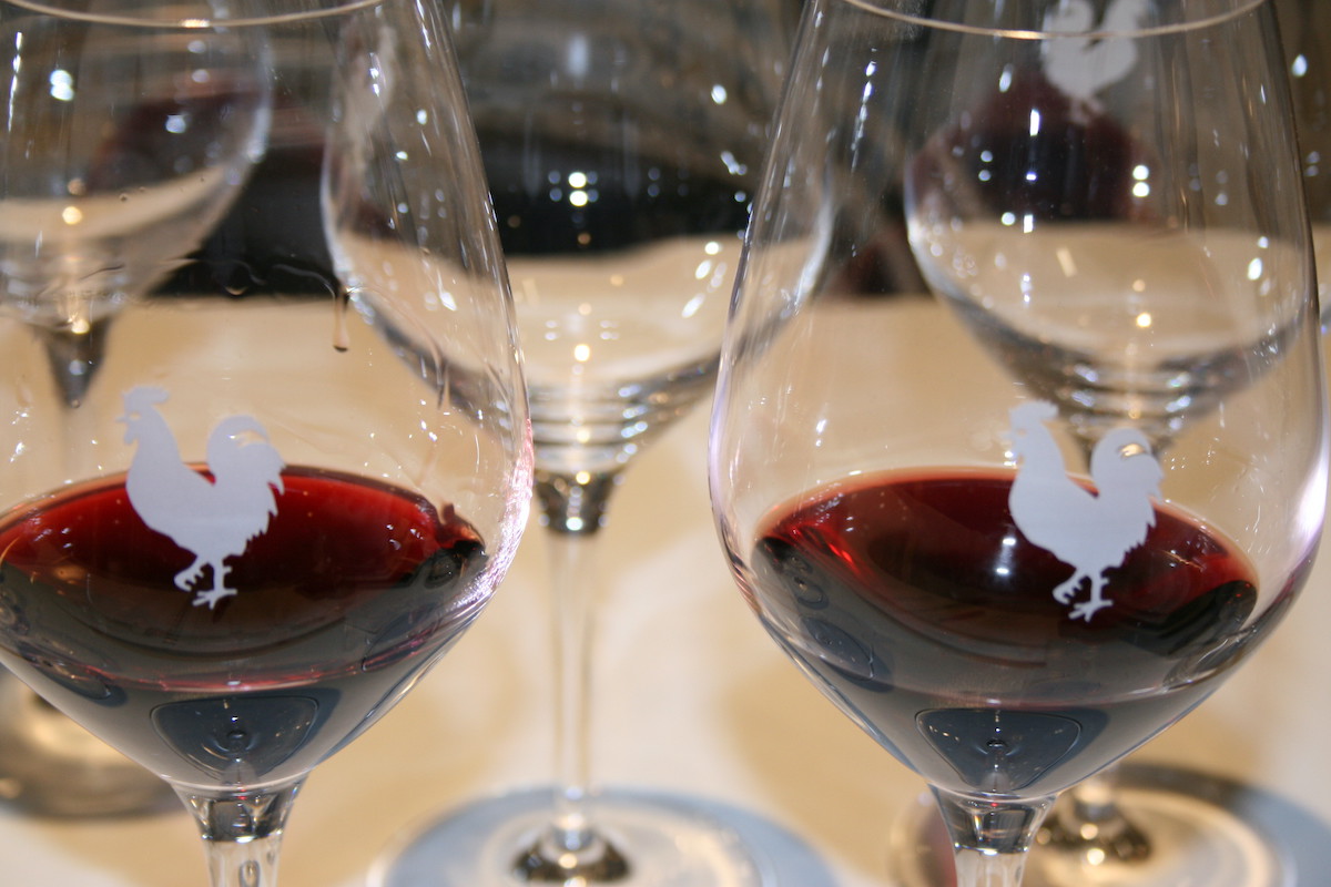Red wine in two glasses decorated with a rooster symbol