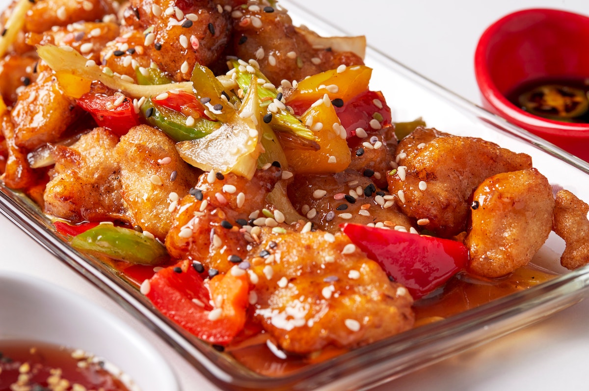 Chinese chicken dish with peppers and sesame seeds in a glass dish