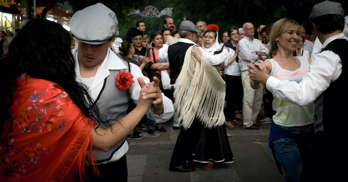 Couples wearing traditional clothing from Madrid do a partners' dance.