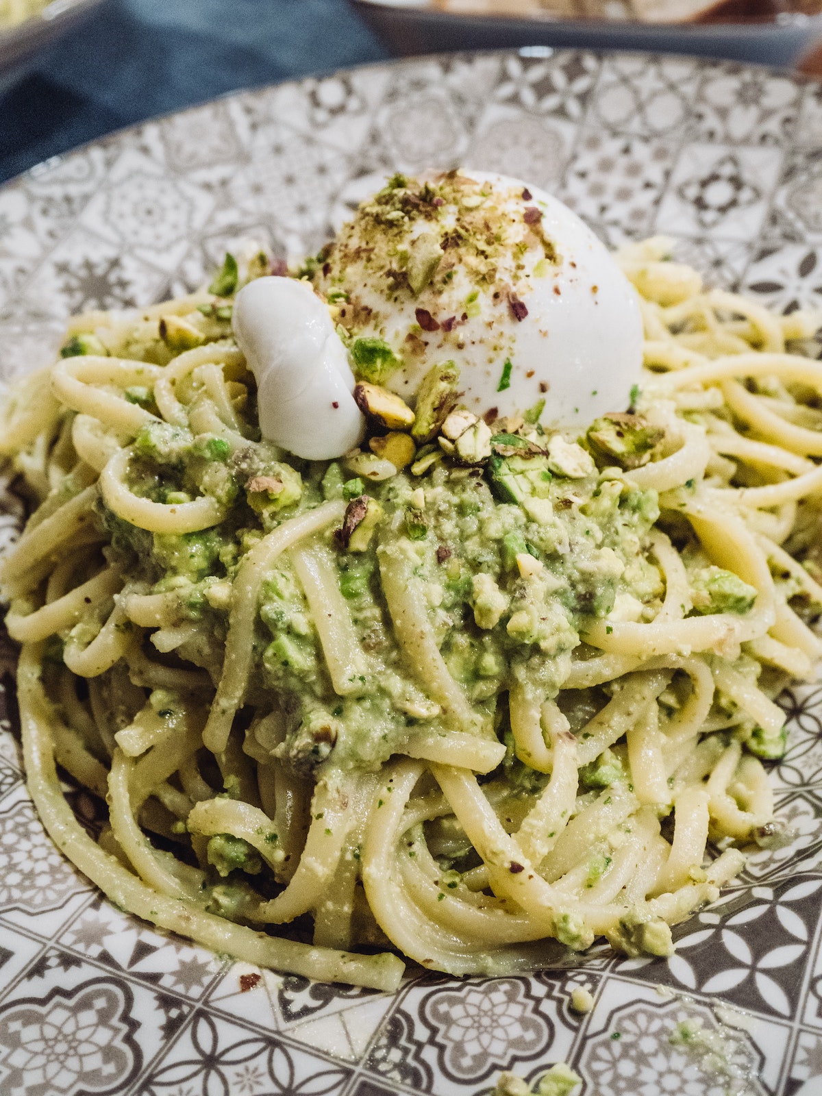 Close up of a vegetarian pasta dish with pistachios and burrata cheese.
