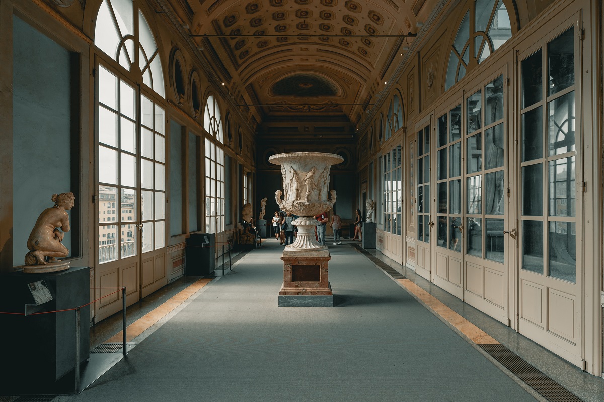 An elegant hallway with curved walls, tall windows and a marble statue in the middle