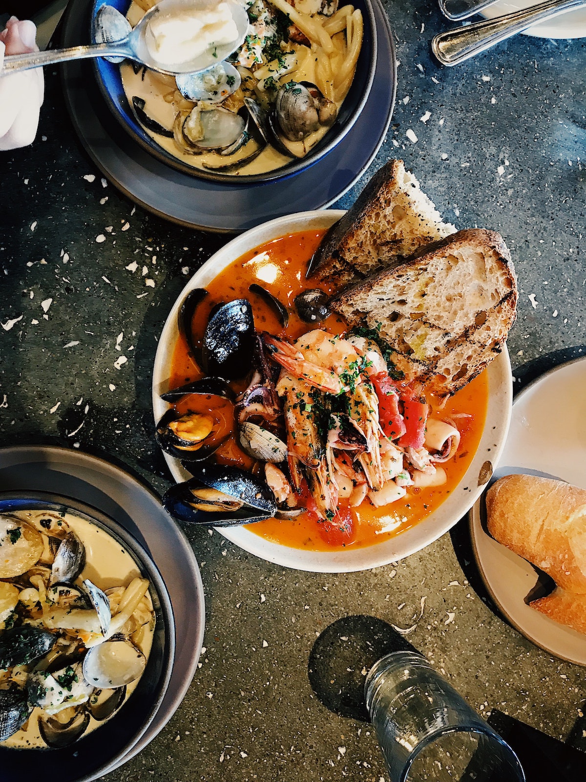 Flatlay of a black table with three large bowls of seafood stew