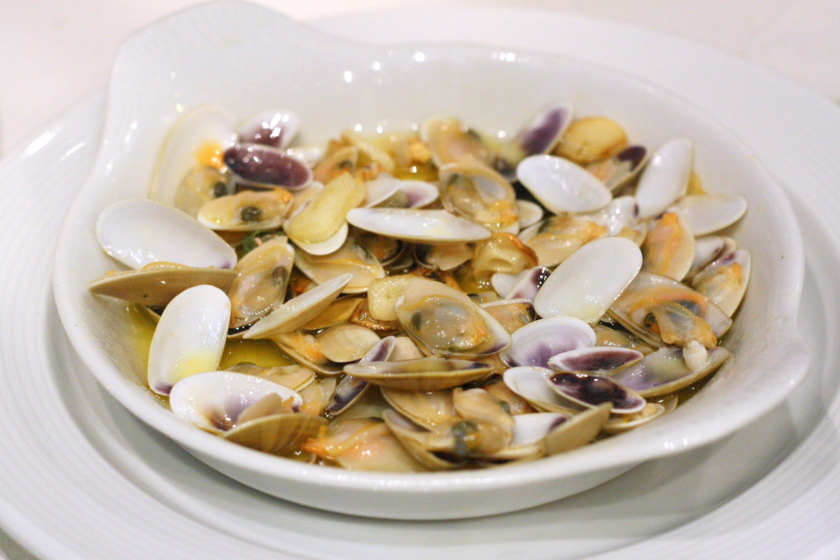 White dish full of small clams.