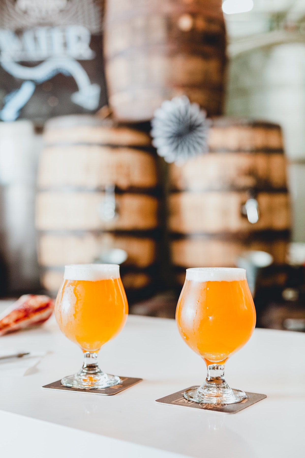 Two light colored beers on a white tabletop