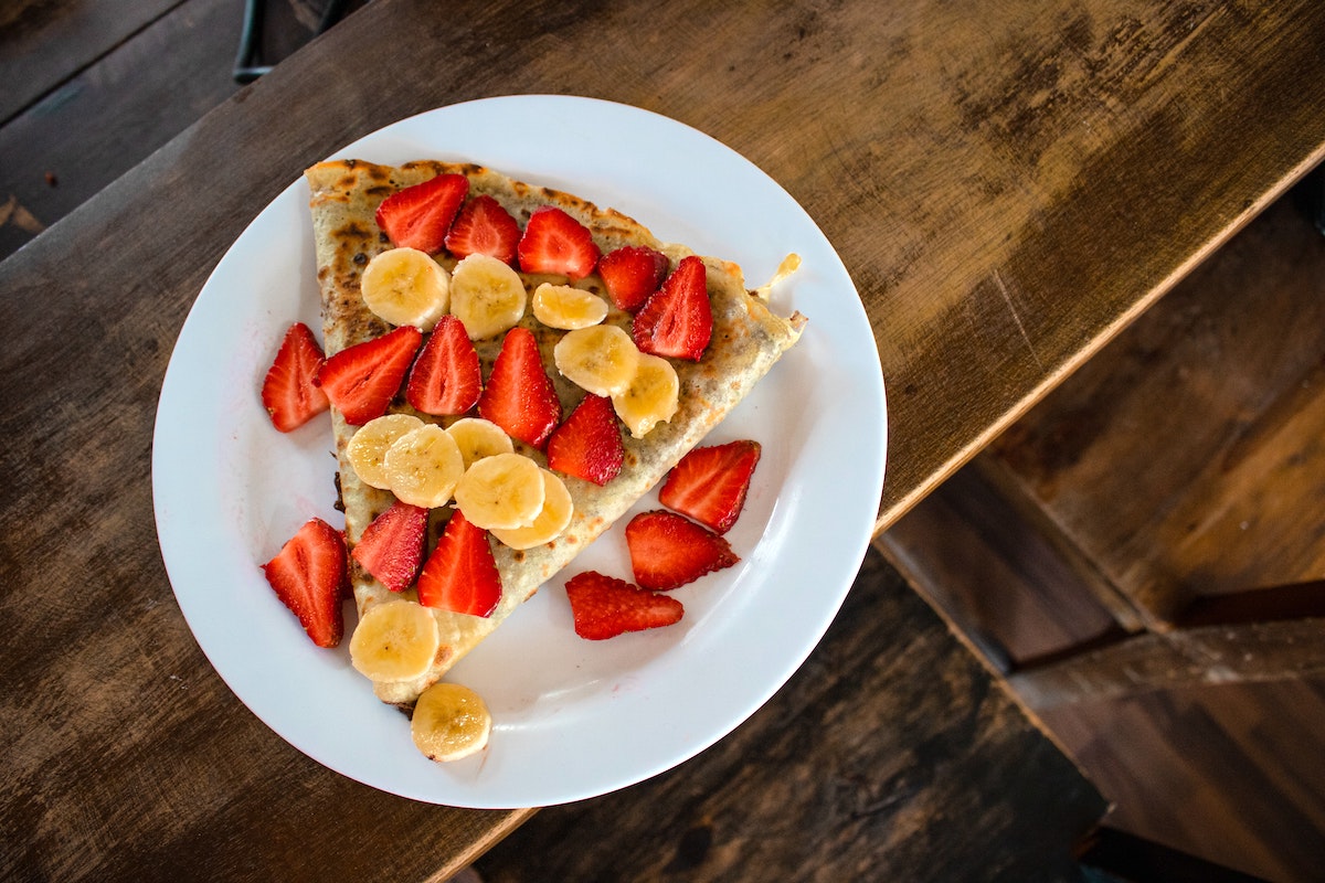 Overhead shot of crepes topped with sliced strawberries and bananas