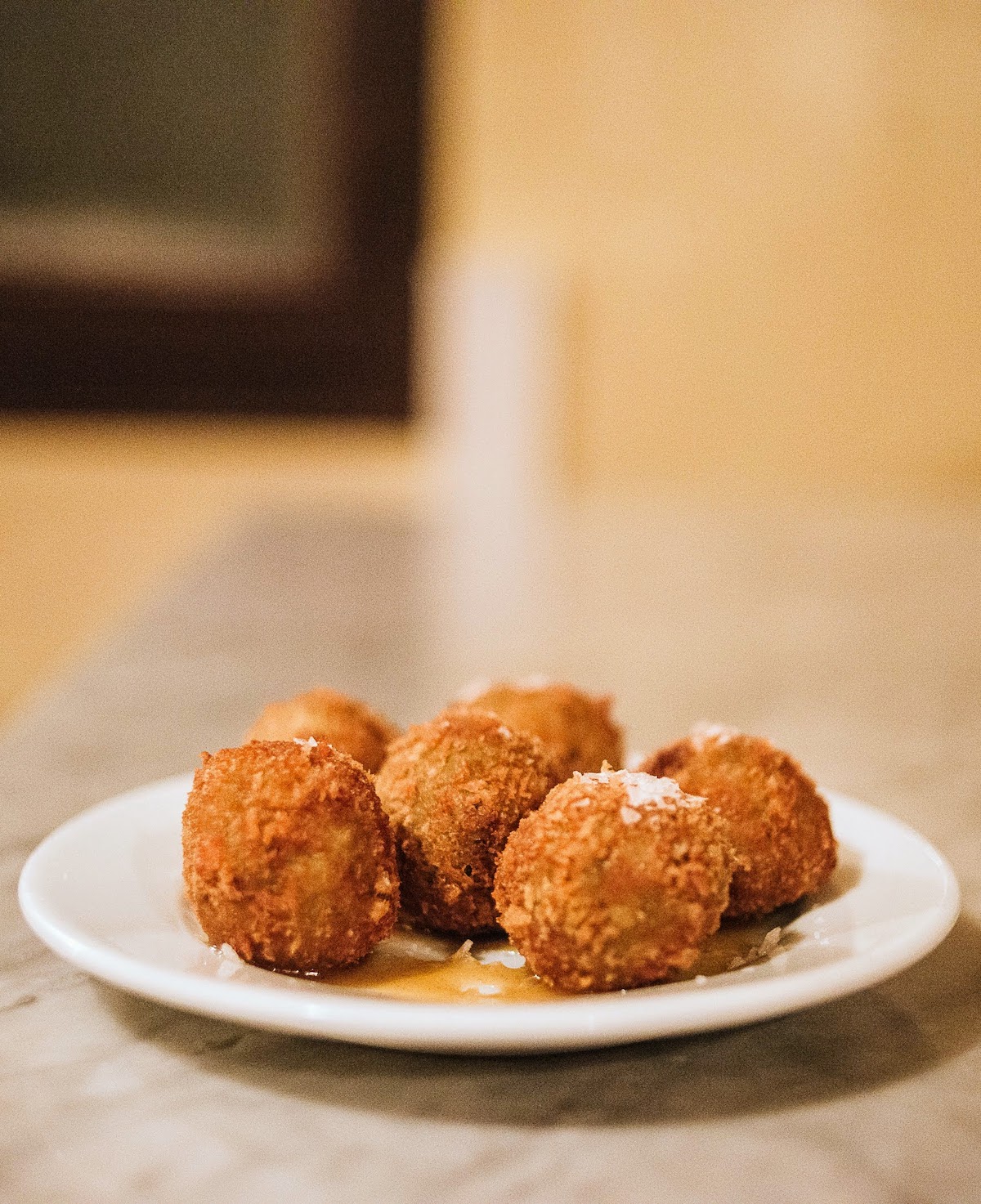Six round croquettes on a white plate