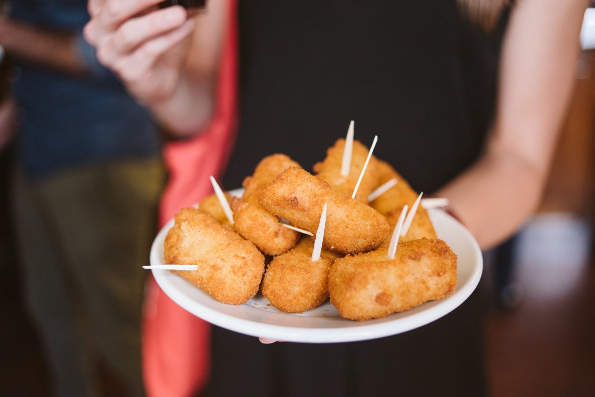 Close up of a plate of fried salt cod croquettes with toothpicks sticking out of them.