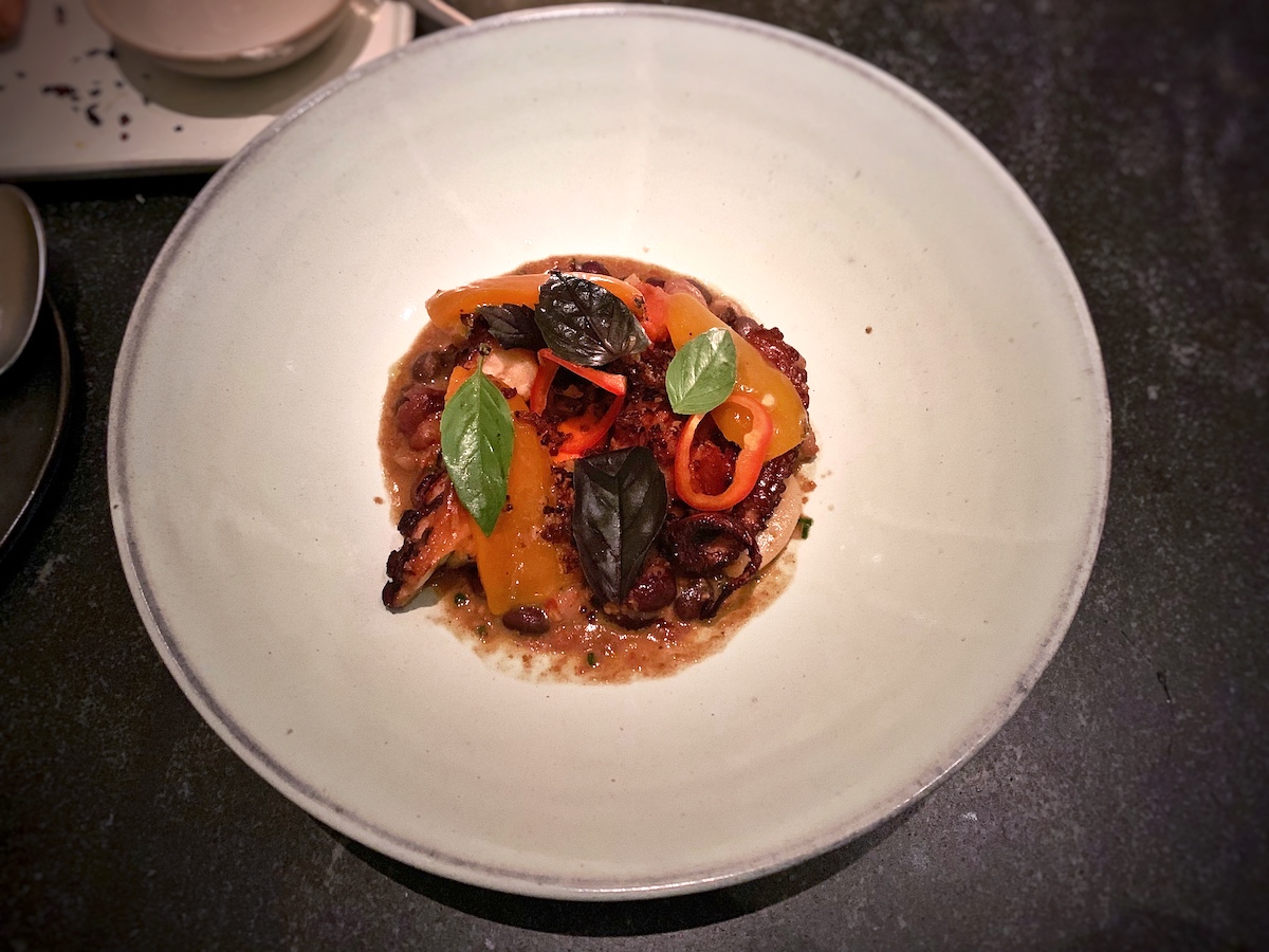 Overhead shot of charred octopus with chorizo and peppers served at a Michelin restaurant in NYC.