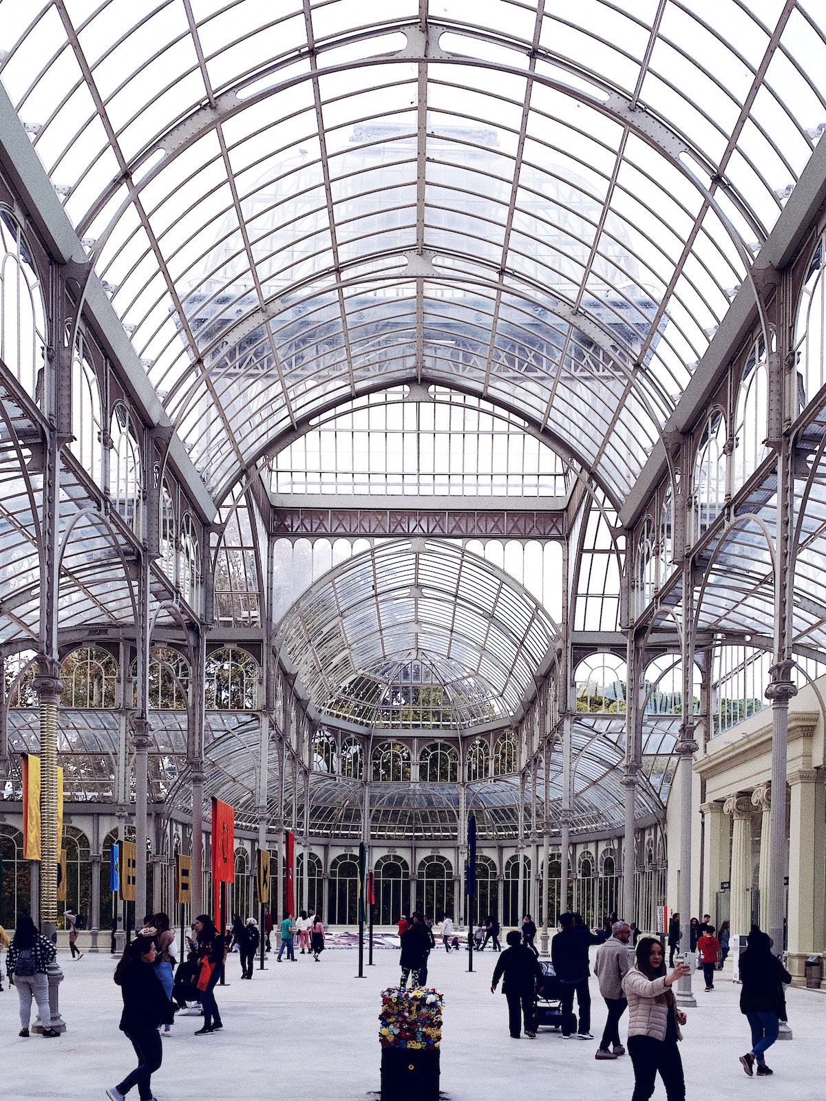 Crowd of people walking around a large indoor space with a curved glass roof.