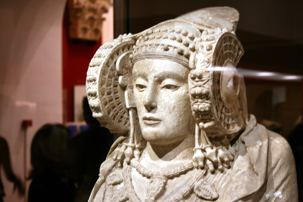 Ancient stone sculpture of a woman wearing an elaborate headdress