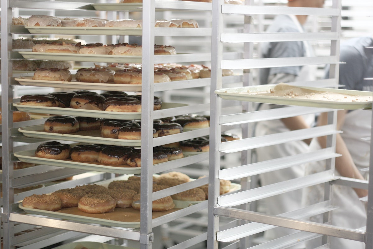 Tall rack of baking trays full of donuts