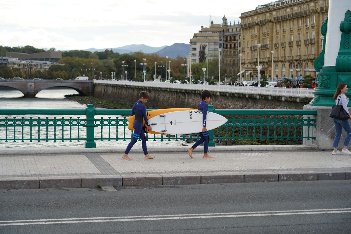 children holding a surfboard walking in San Sebastian