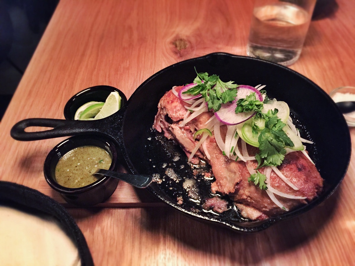 Duck carnitas in a cast-iron skillet with cilantro, raddish, and onion