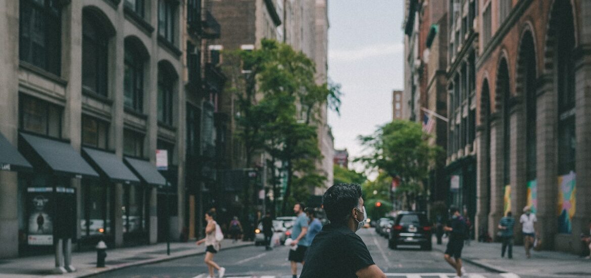 Man wearing shorts and a black T-shirt riding a bike on a city street