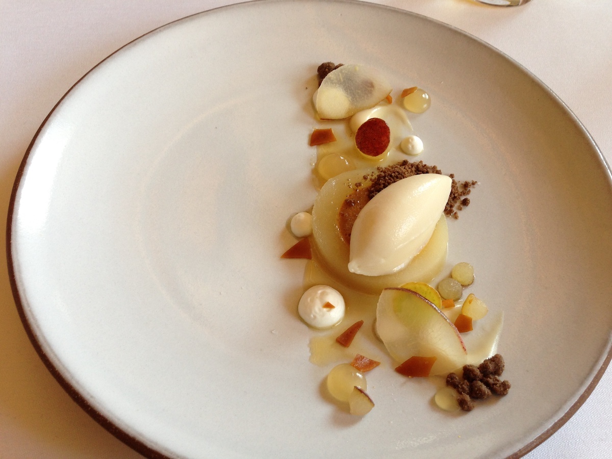 Modern presentation of poached pear dessert with pear sorbet on a white plate
