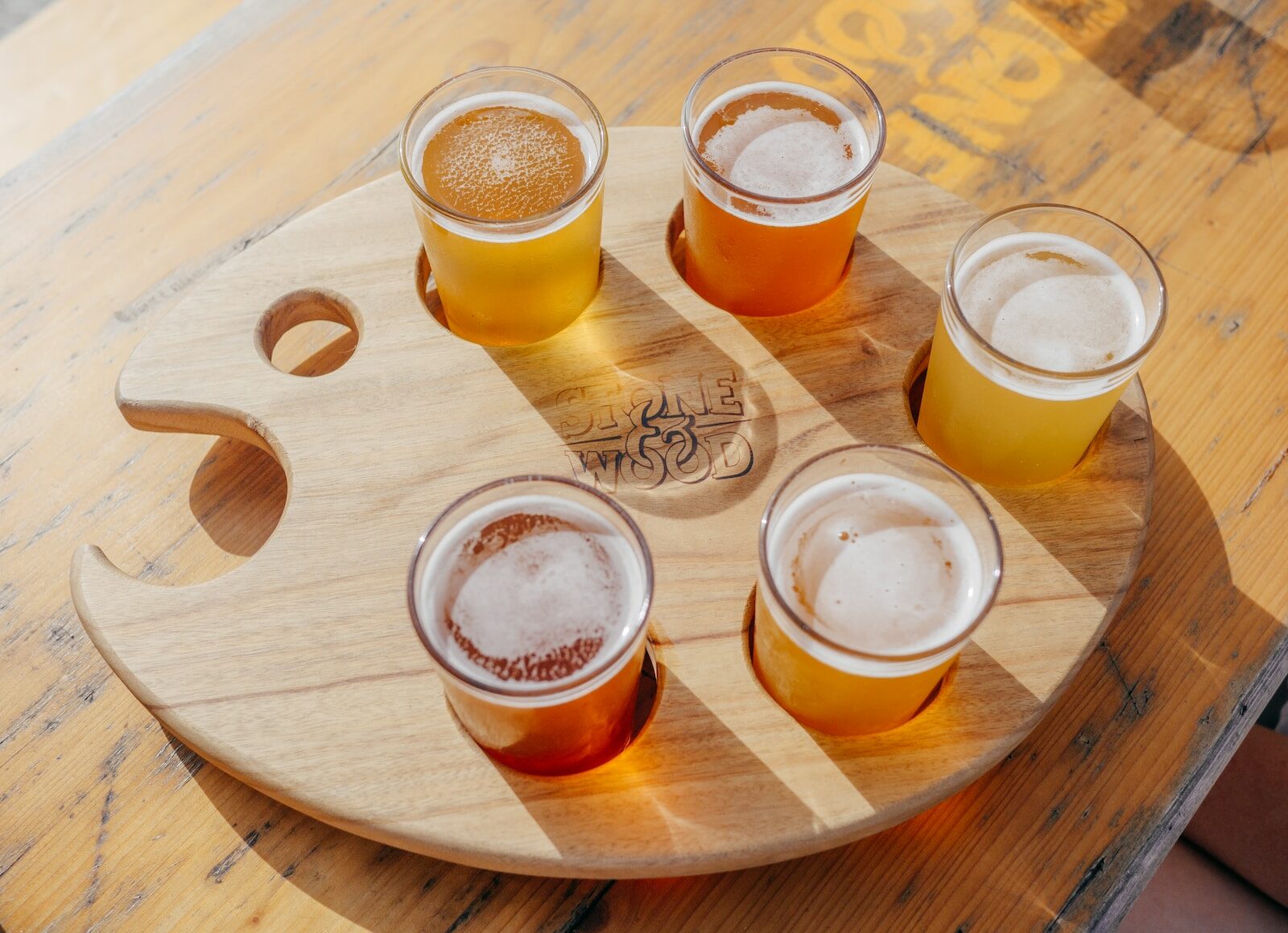 five poured drinking glasses on brown wooden tray