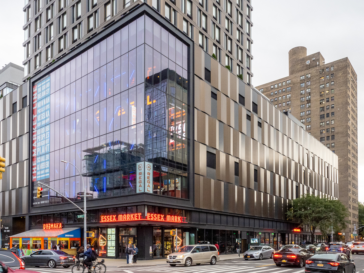 Modern glass-fronted building on a busy street corner in New York City