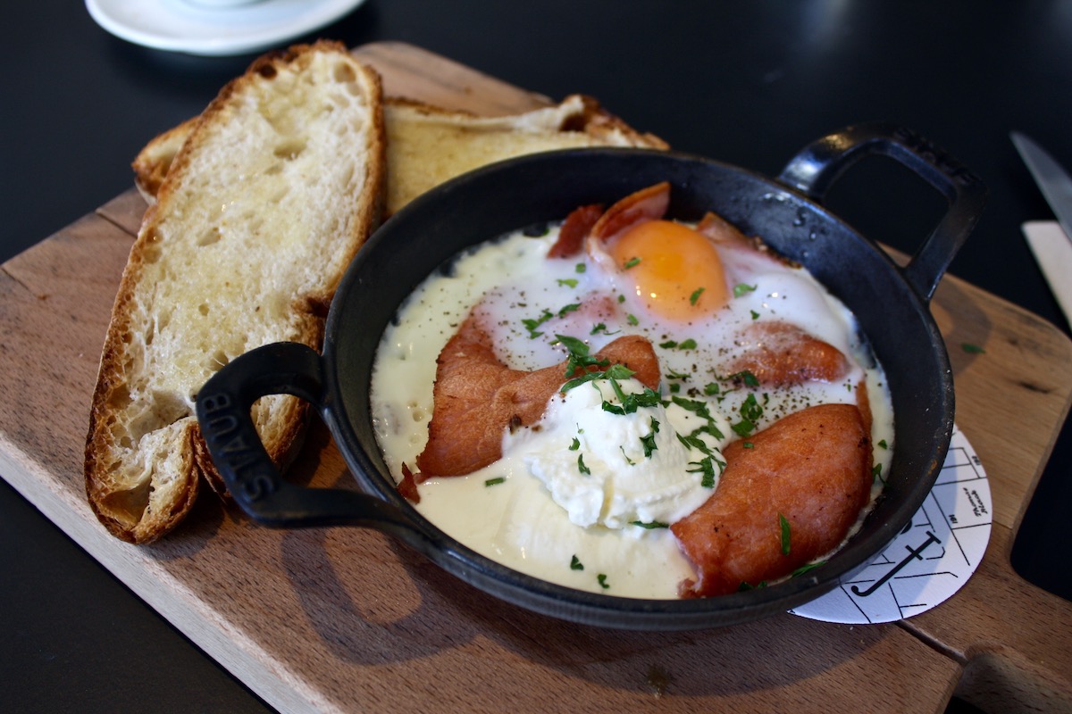 Egg dish served in a small black bowl with bread on the side