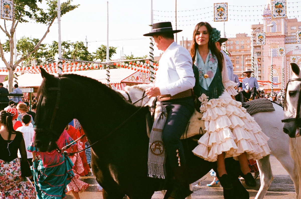 A couple in traditional clothing from southern Spain rides on horseback.