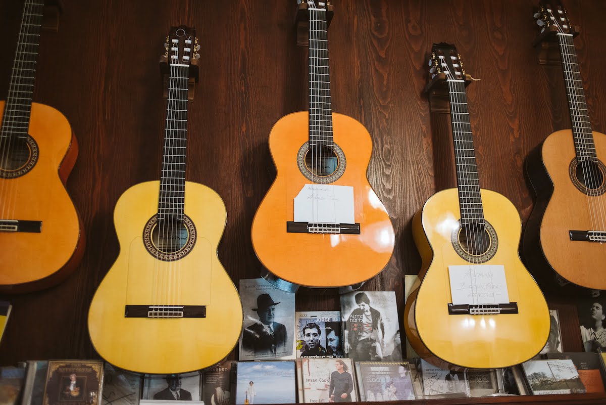 Five flamenco guitars hanging on the wall of a shop.