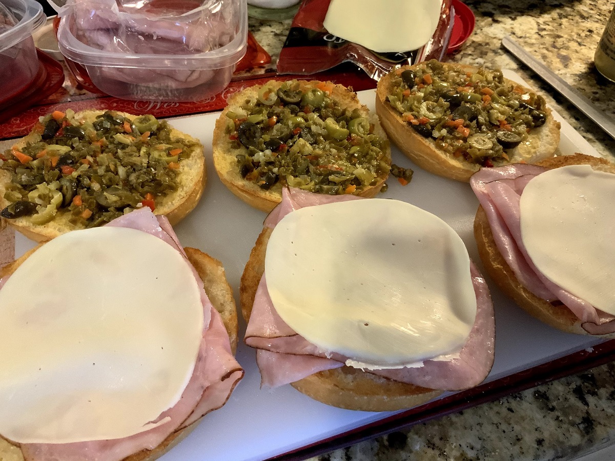 Muffuletta sandwiches in the making with olives, bread, ham and cheese