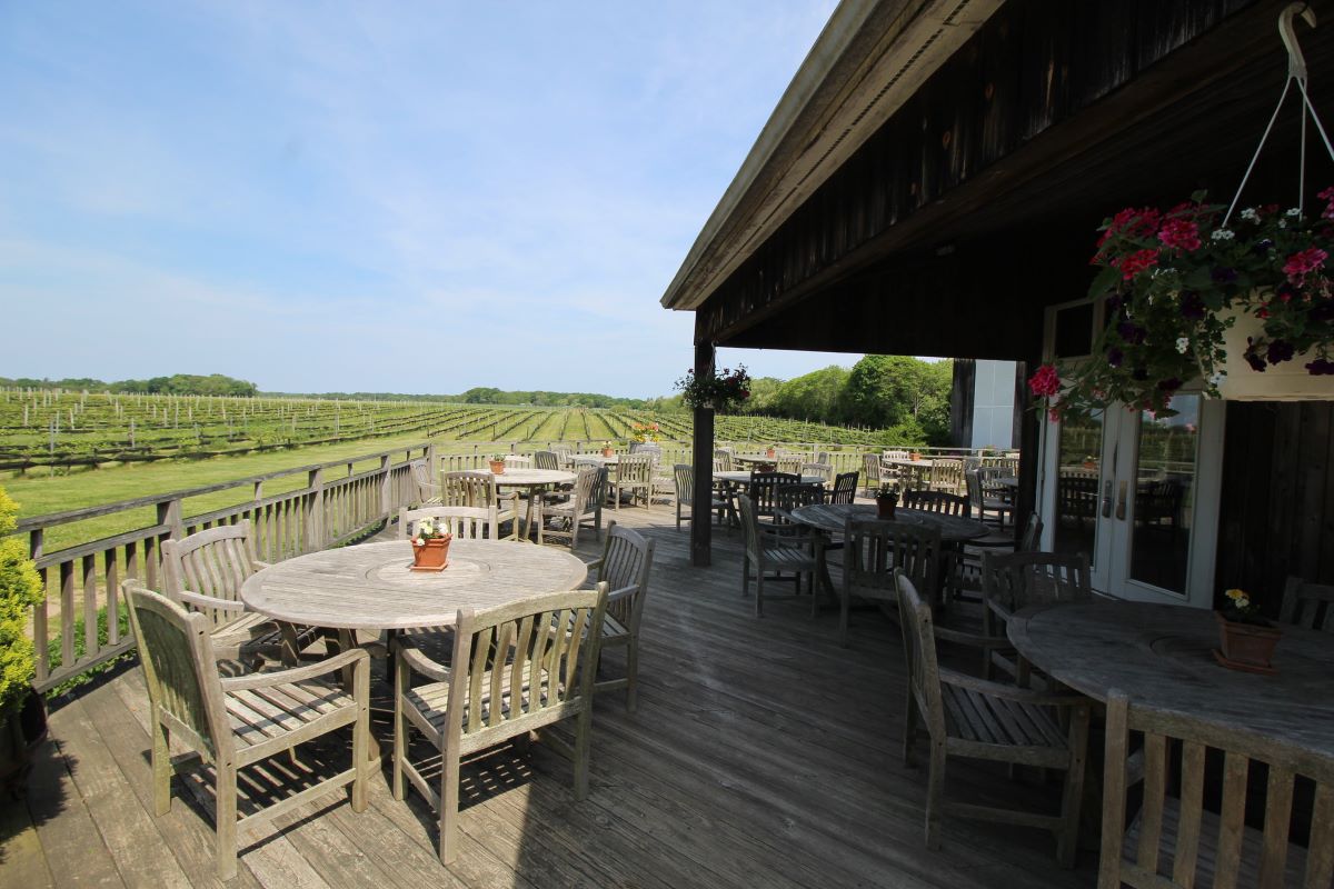 wooden deck with wooden tables and chairs overlooking vineyard 