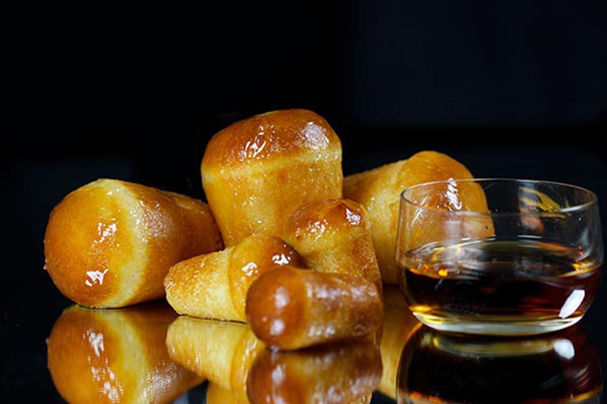 Classic neapolitan pastry baba with glass of rum and black background