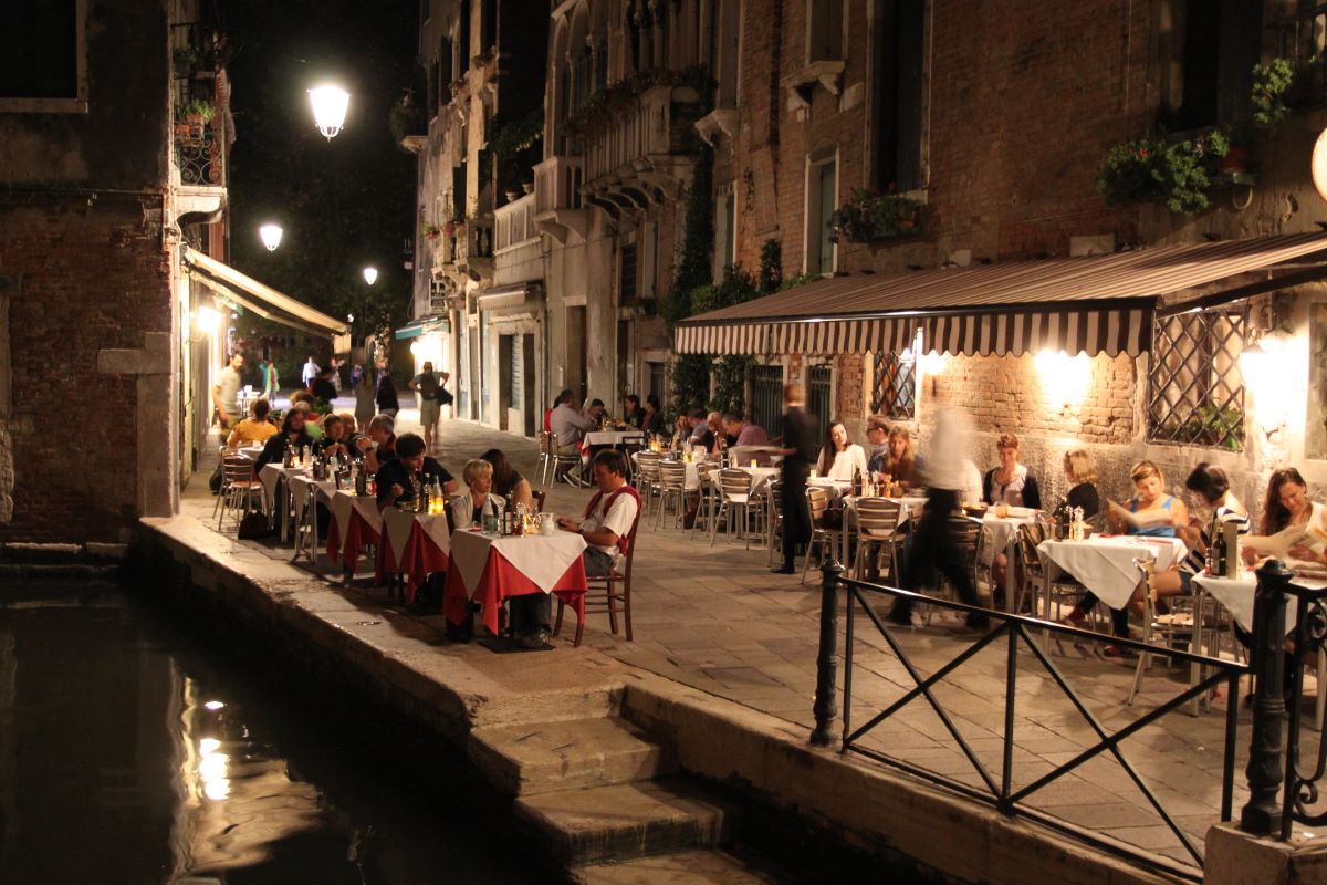 people seating at restaurant at night by canal