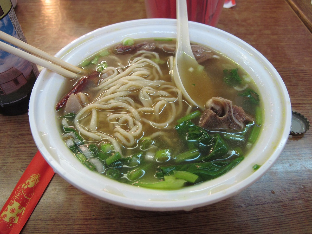 Large bowl of soup with beef, greens, and handpulled Chinese noodles