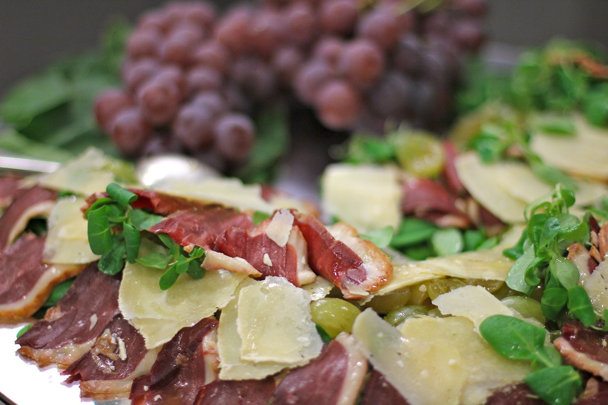 Board of cured Italian meats and cheeses with grapes and Tuscan bread