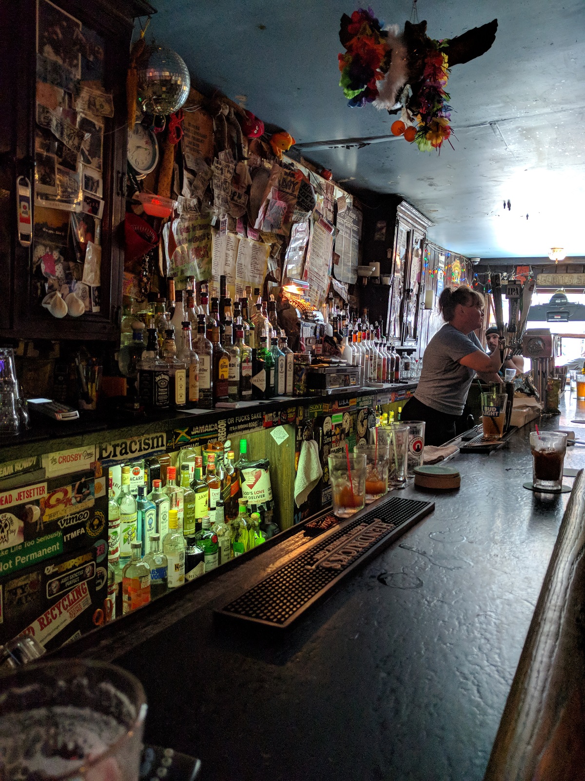 View behind the bar of a dive bar with many colored bottles of liquor
