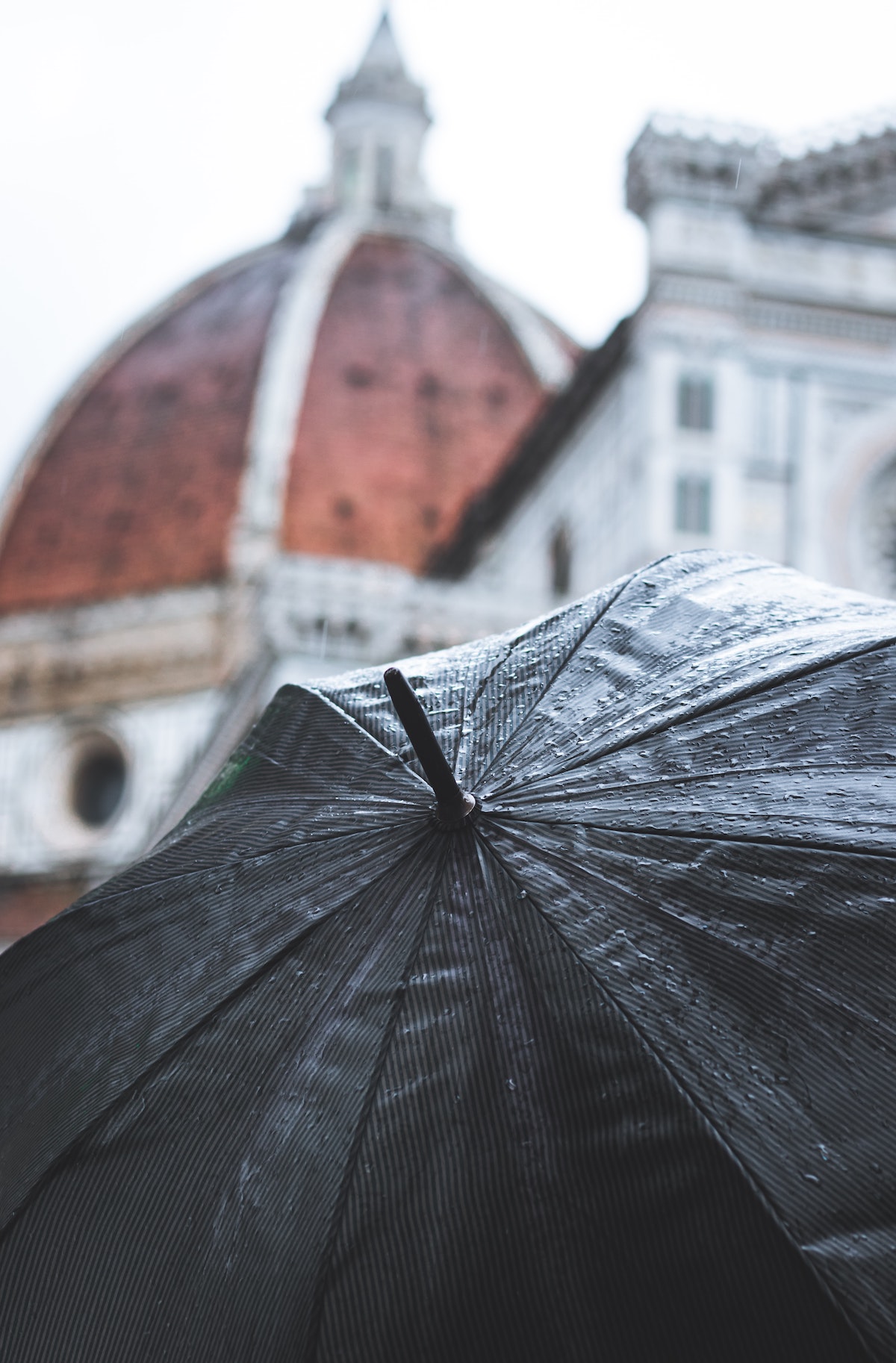 View of Florence, Italy's cathedral dome as seen from above a black umbrella on a rainy day