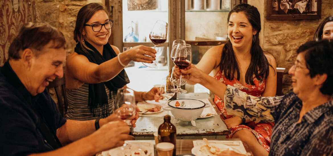 Group of people toasting with red wine around a table