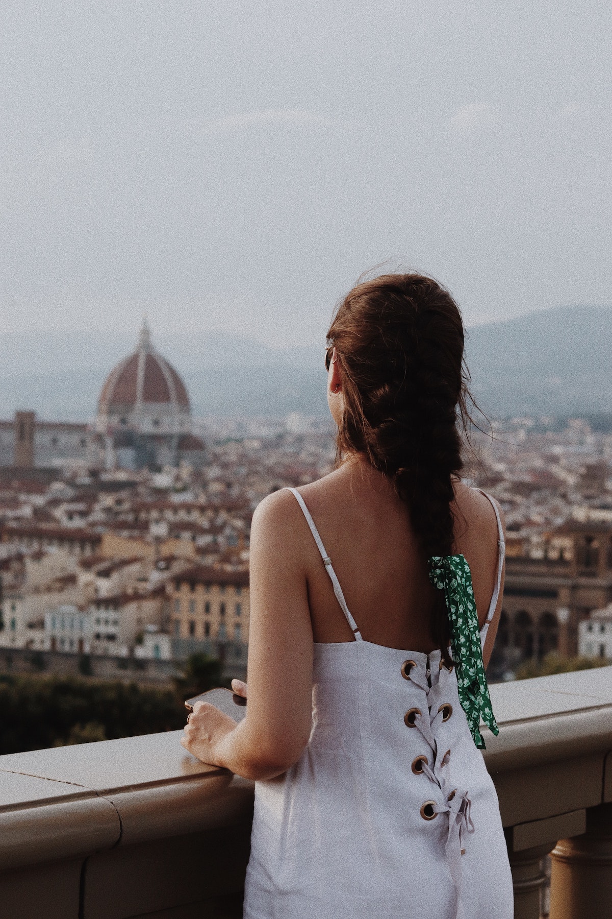 A woman in a white dress looking out over the city of Florence