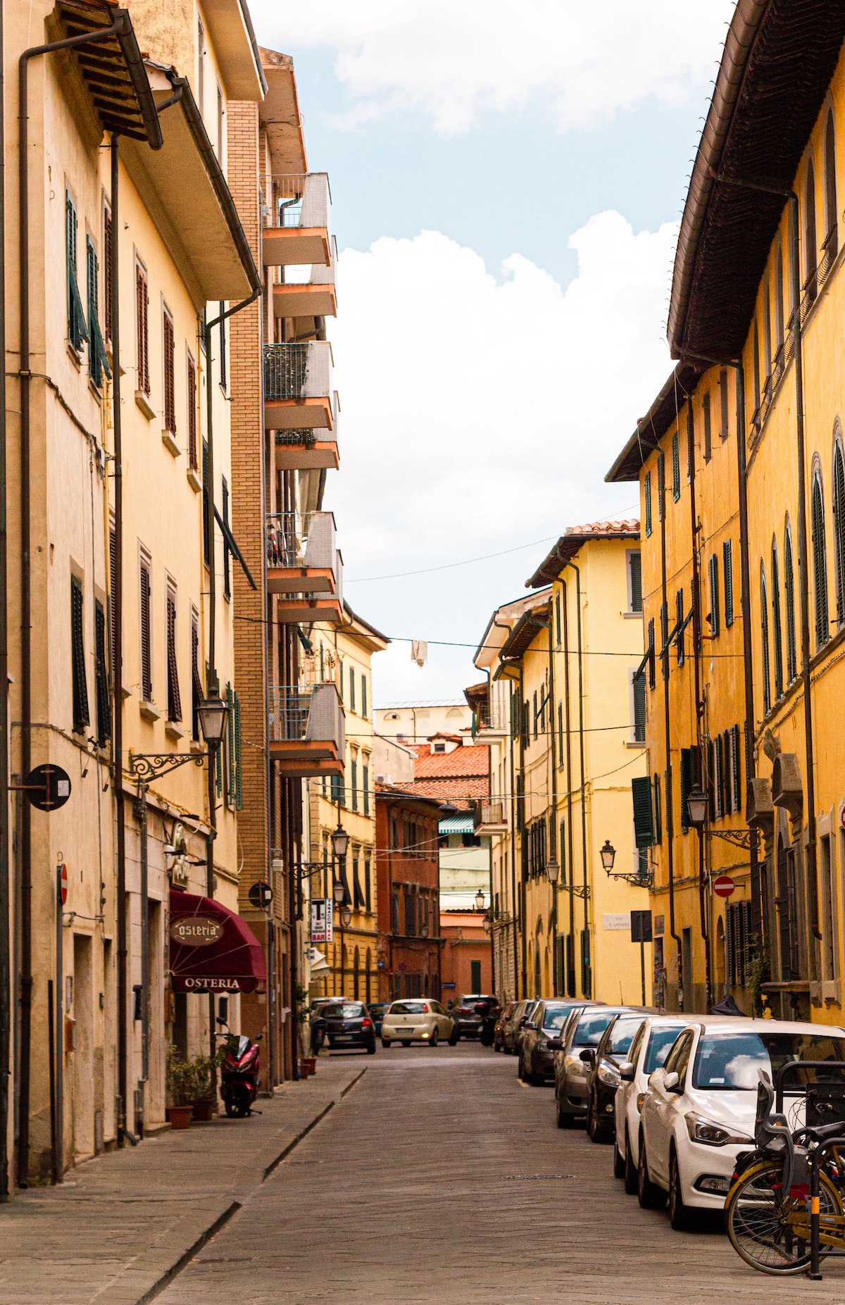Light-colored multi-story buildings lining a narrow street in Florence, Italy