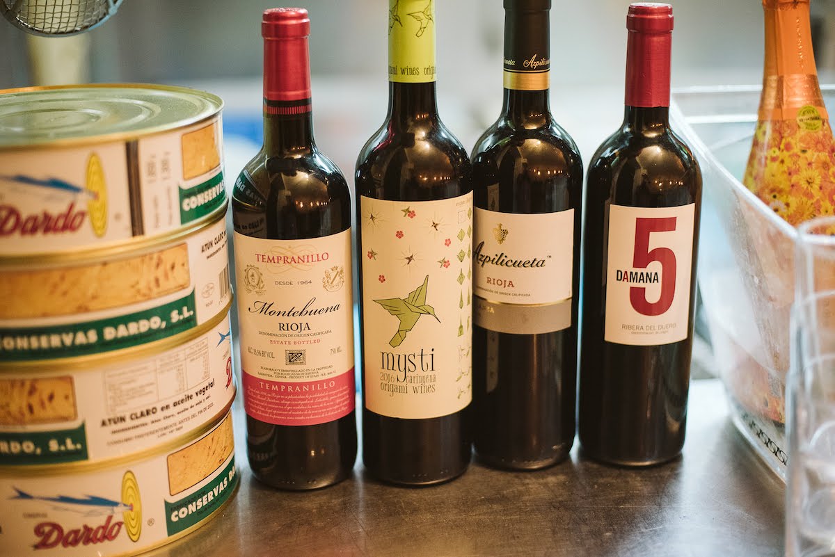 Four bottles of Spanish wine beside a stack of three cans of tuna