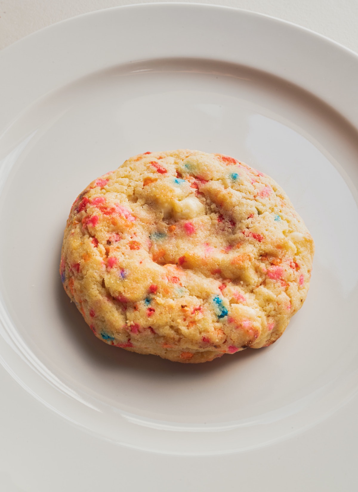 Cookie with rainbow funfetti sprinkles on a white plate