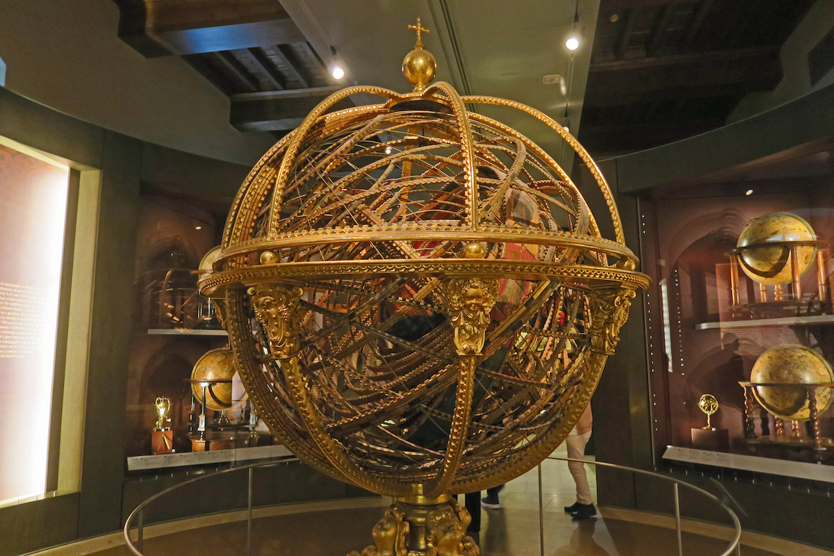 Large metal sphere with intricate gold details on display in a museum