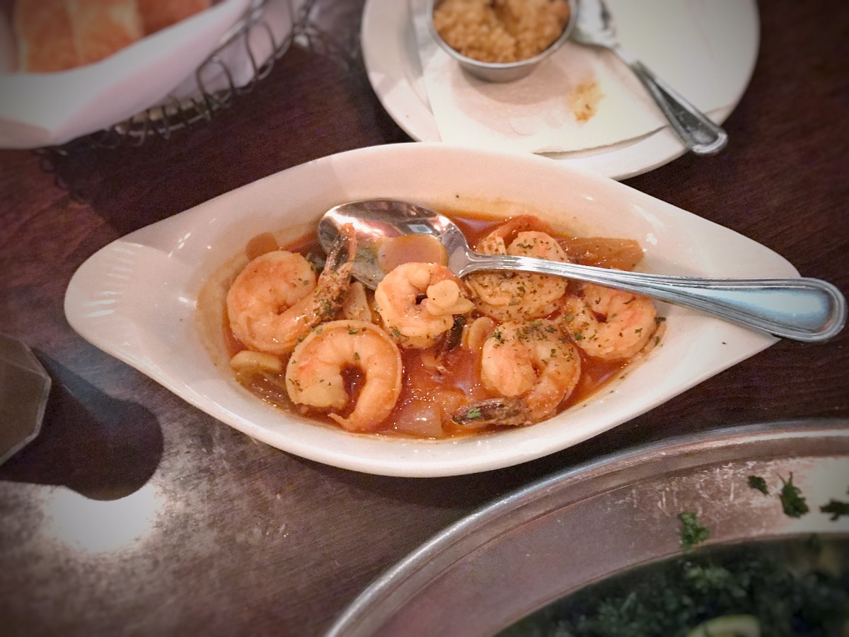 Dish of shrimp in a garlic sauce with spoon on restaurant table