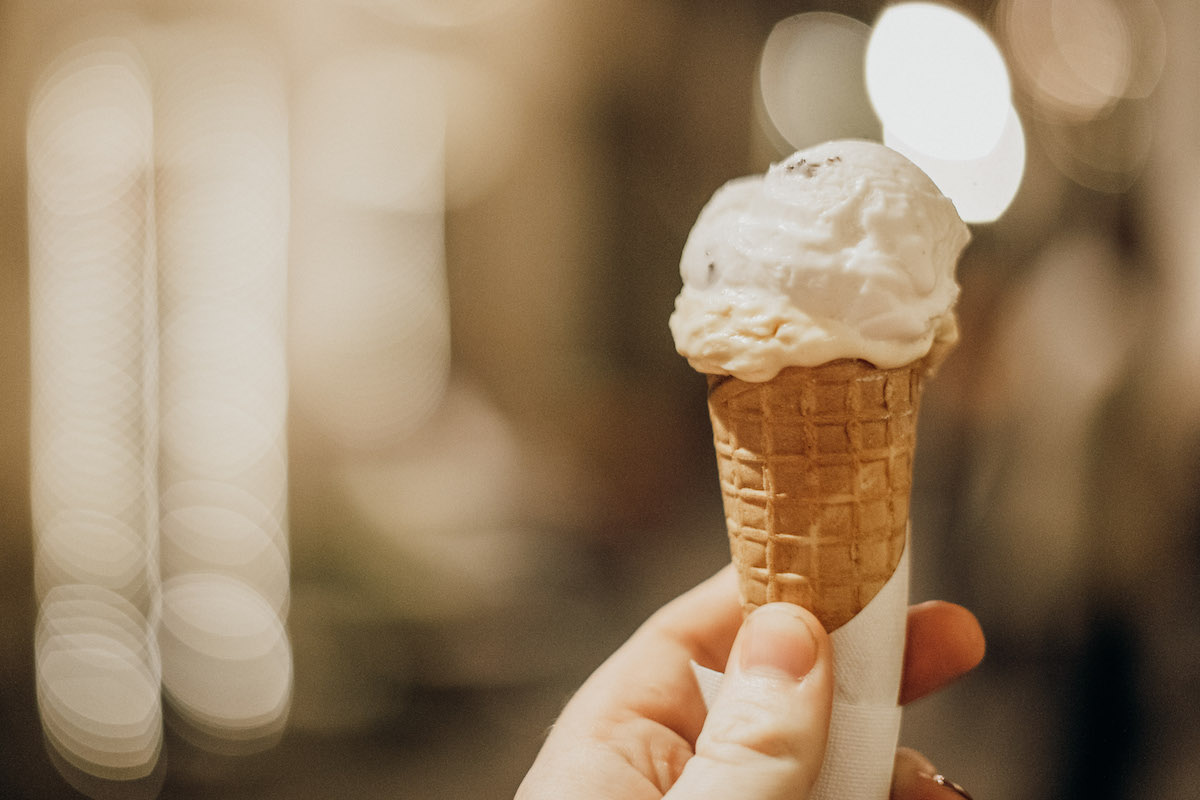 Person's hand holding a cone with a small scoop of gelato