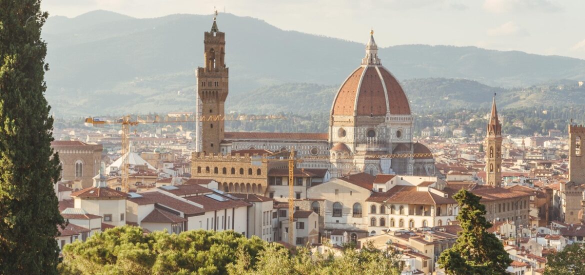 A mountain view of Florence with green trees in the foreground with the Duomo in the background
