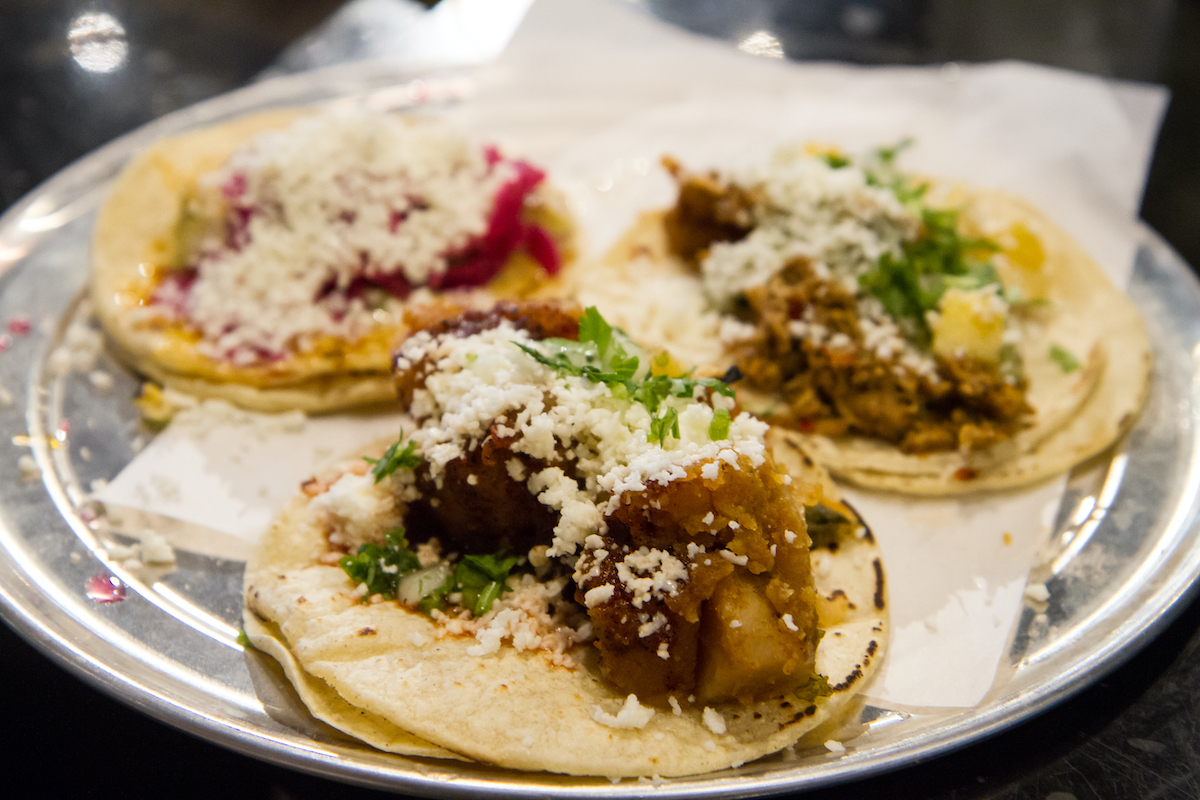 three tacos with different toppings on a round platter