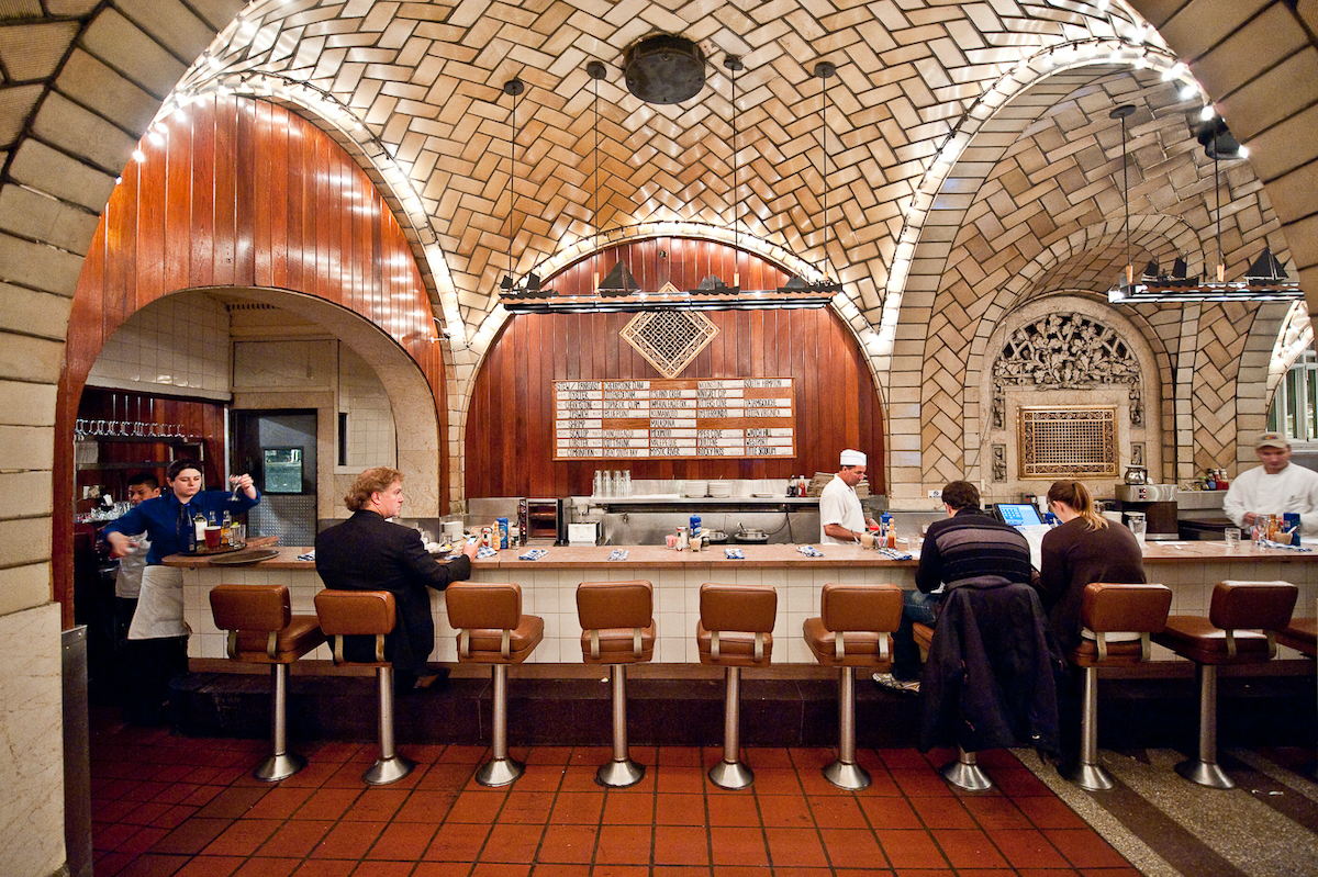 People sitting at a bar with large curved ceilings overhead and rectangular tiles on walls