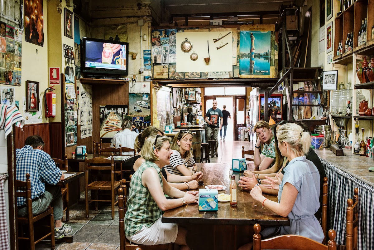 A group of people sitting around a table inside a quirky local bar in Barcelona.