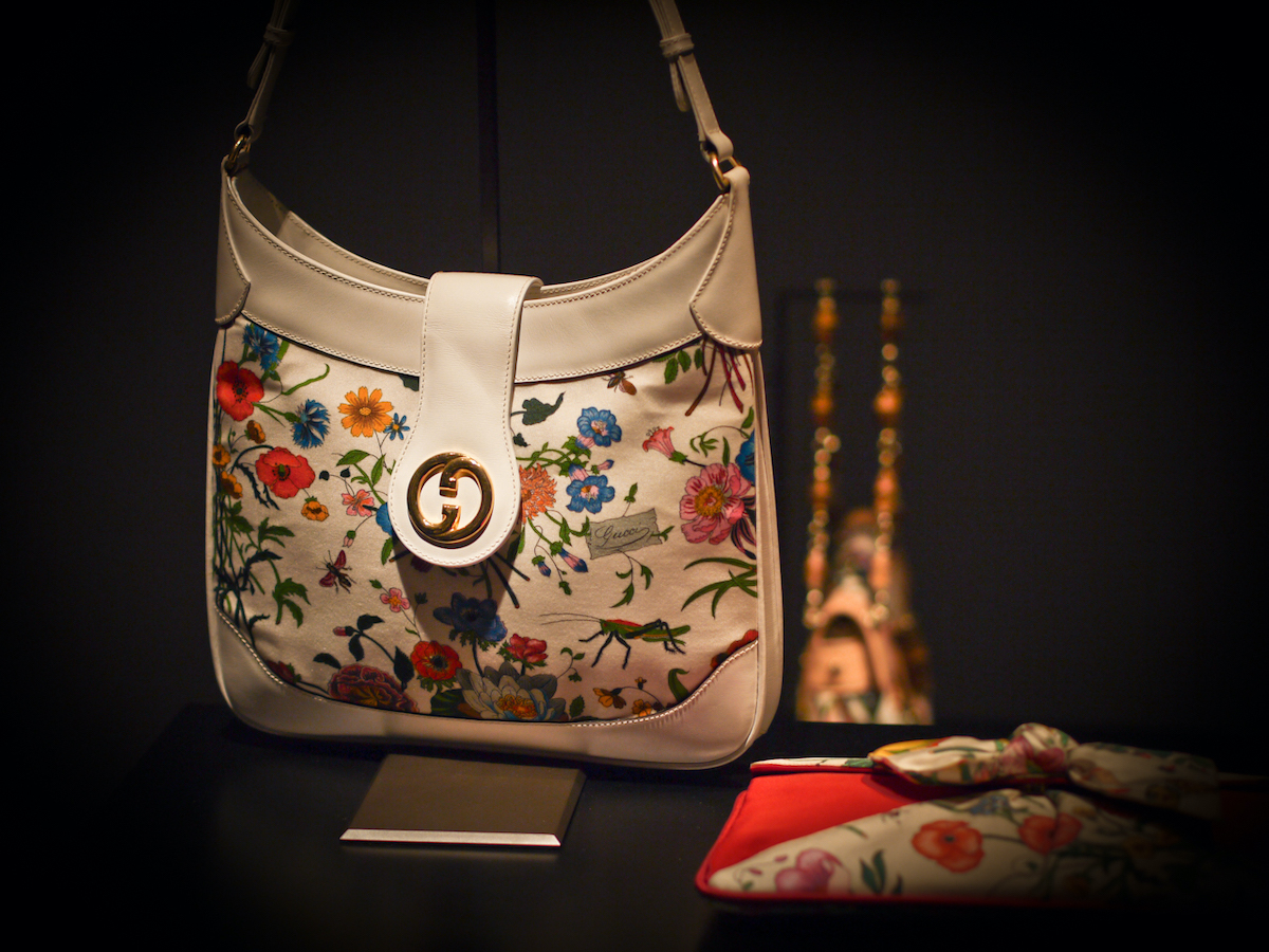 Gucci handbag and wallet with floral print displayed against a black background