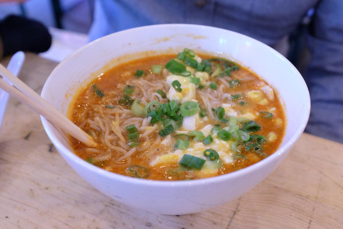 Bowl of ramen with a red broth and topped with scallions