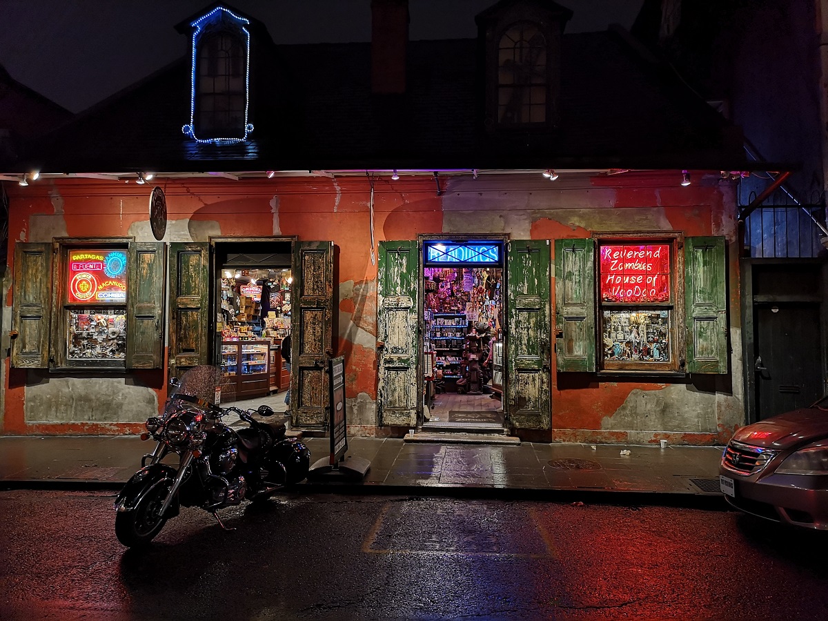 Spiritual botanica shop in New Orleans at night with signs of palm reading and voodoo dolls