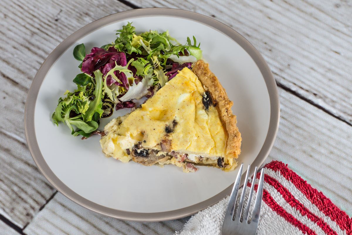 mushroom quiche and salad on wooden table