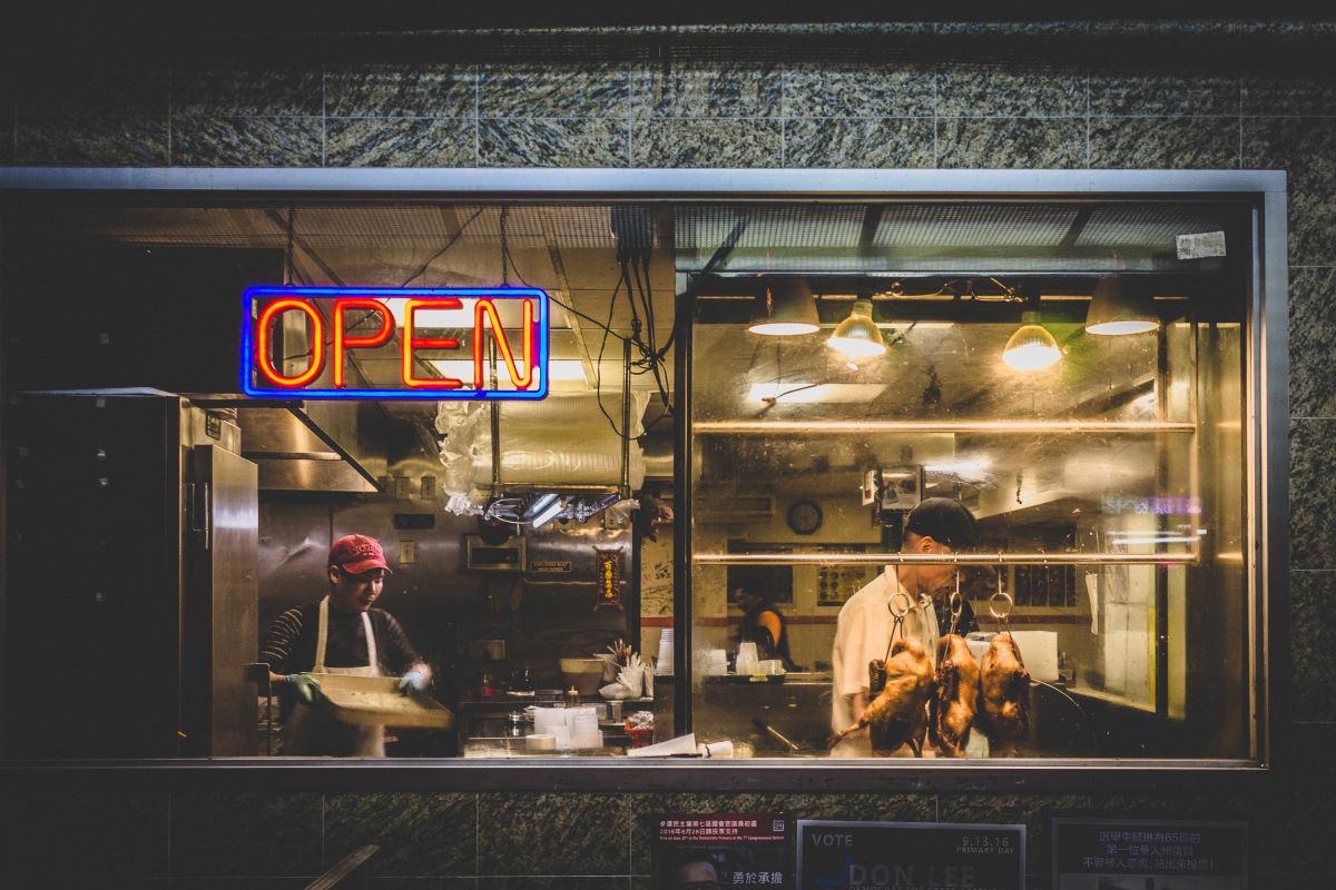 men cooking inside restaurant with neon light